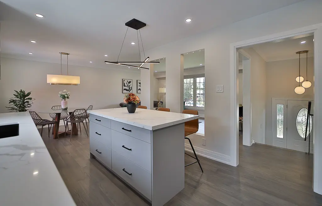Kitchen island with quartz counters and a modern chandelier over the dining area — 41 Springhome, Barrie